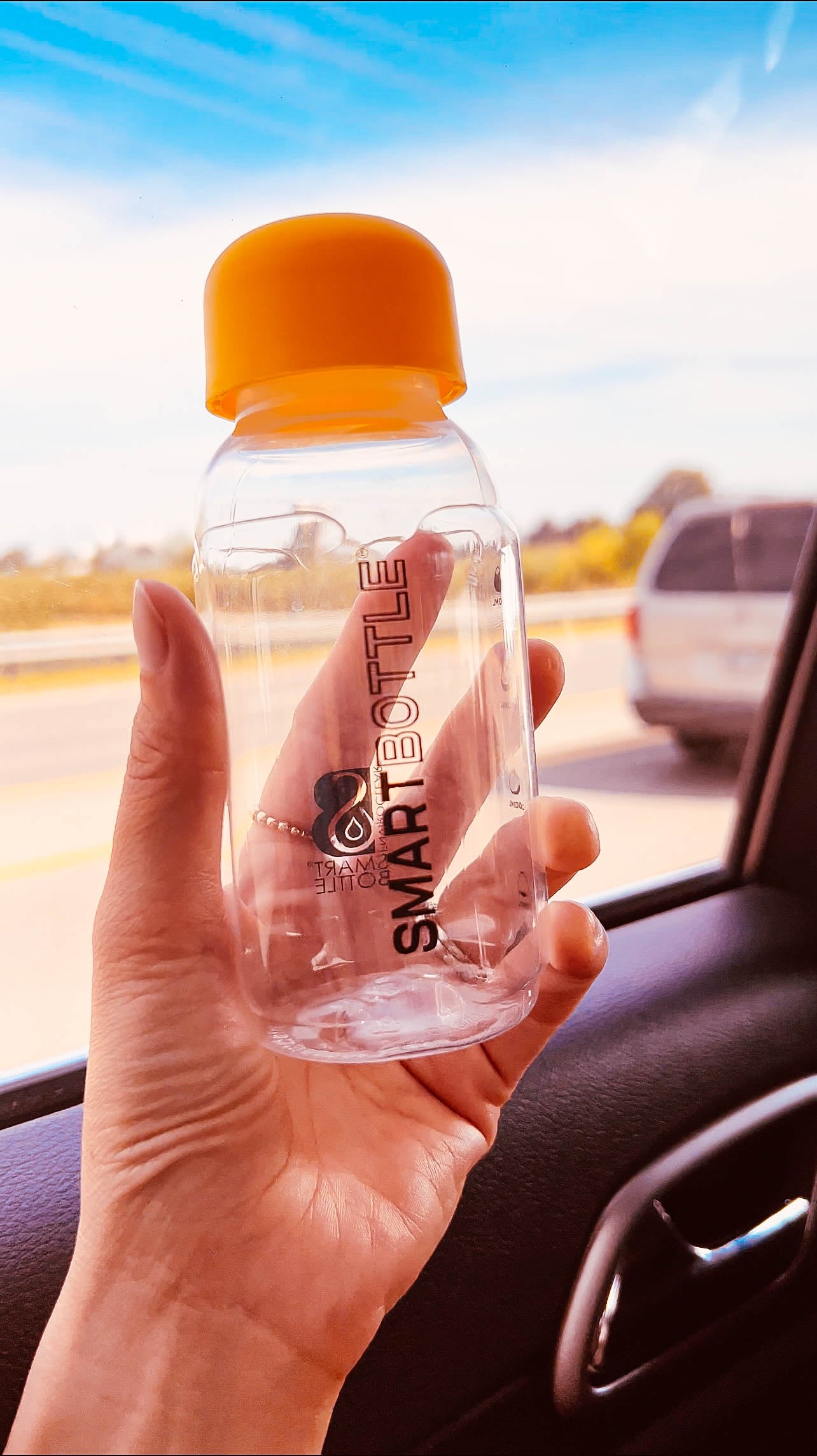 hand holding an empty 250ml Smartbottle in the car