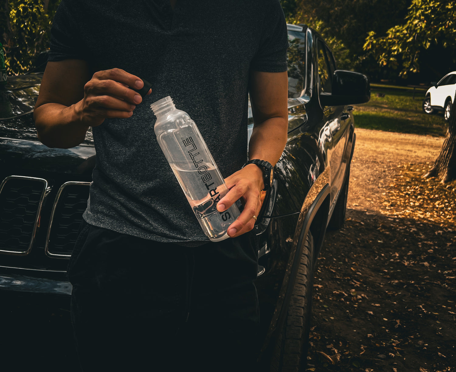 a man in front of the car holding his smartbottle