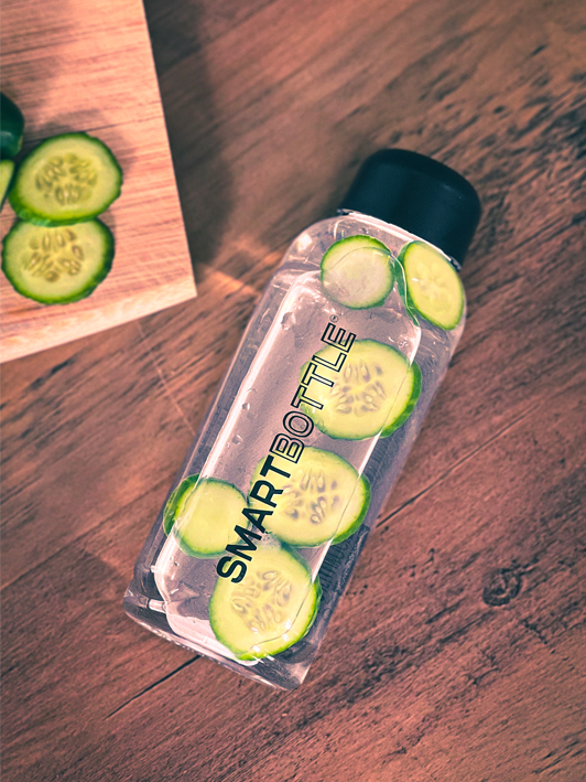 Smartbottle on top of a wooden table with cucumber concoction